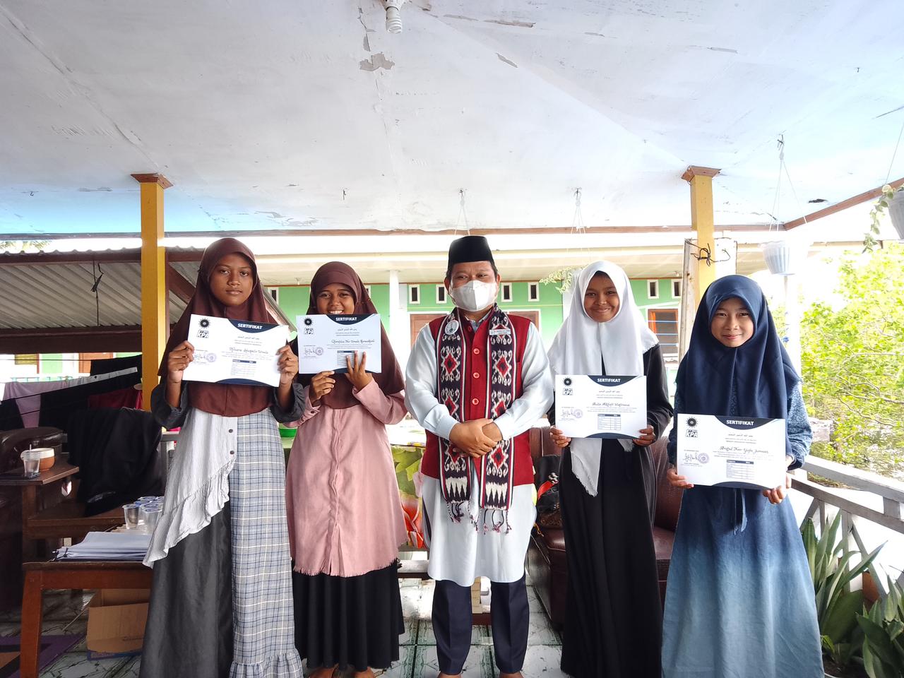 Mubaligh Daerah Papua Barat, Maulana Rakeeman R.A.M Jumaan diapit oleh empat peserta KPA 2022 yang tengah memegang sertifikat hasil mengikti KPA, Kamis 29/12/2022. (Foto : Mln. Rakeeman R.A.M Jumaan)